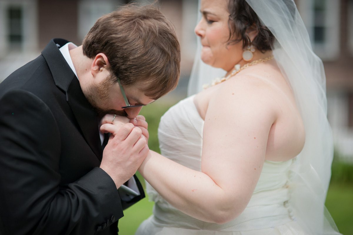 A Unity Tree Ceremony groom kissing brides hand in an emotional moment